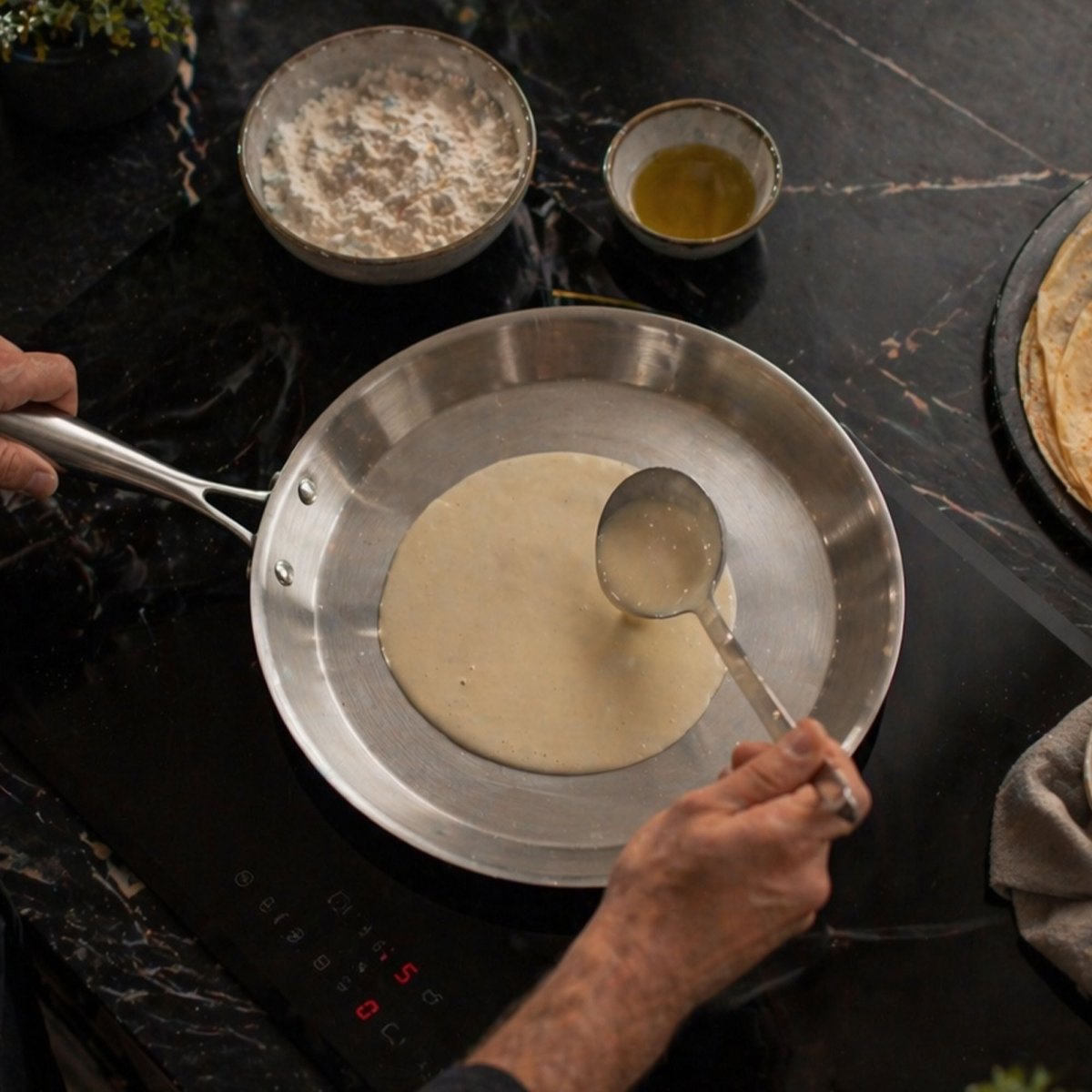 Crêpière Triply 28cm en acier inoxydable sur plaque induction, préparation pâte à crêpes en cours