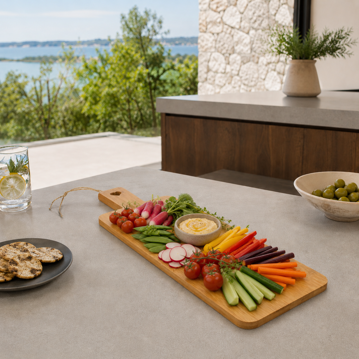 Planche à découper bambou 51x15cm avec légumes frais et hummus, vue en situation sur terrasse avec vue lac