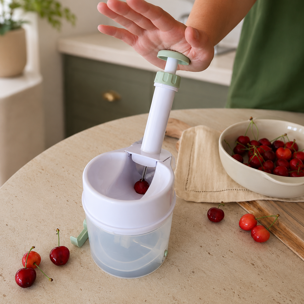Dénoyauteur à cerises en action, main appuyant sur le mécanisme à ressort pour retirer le noyau d'une cerise