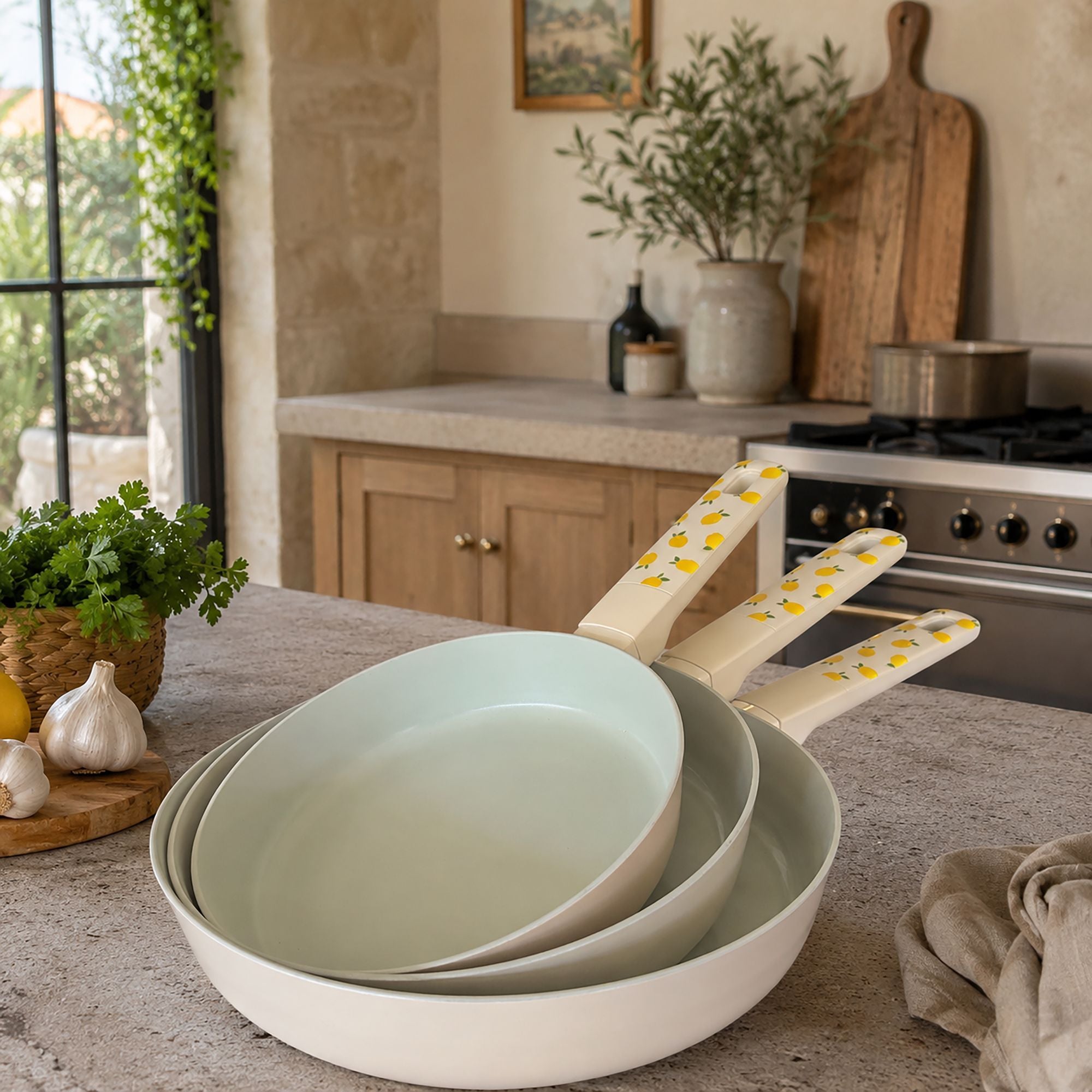 Lot de 3 poêles Citron en aluminium crème avec motifs citrons jaunes, posées sur plan de travail cuisine