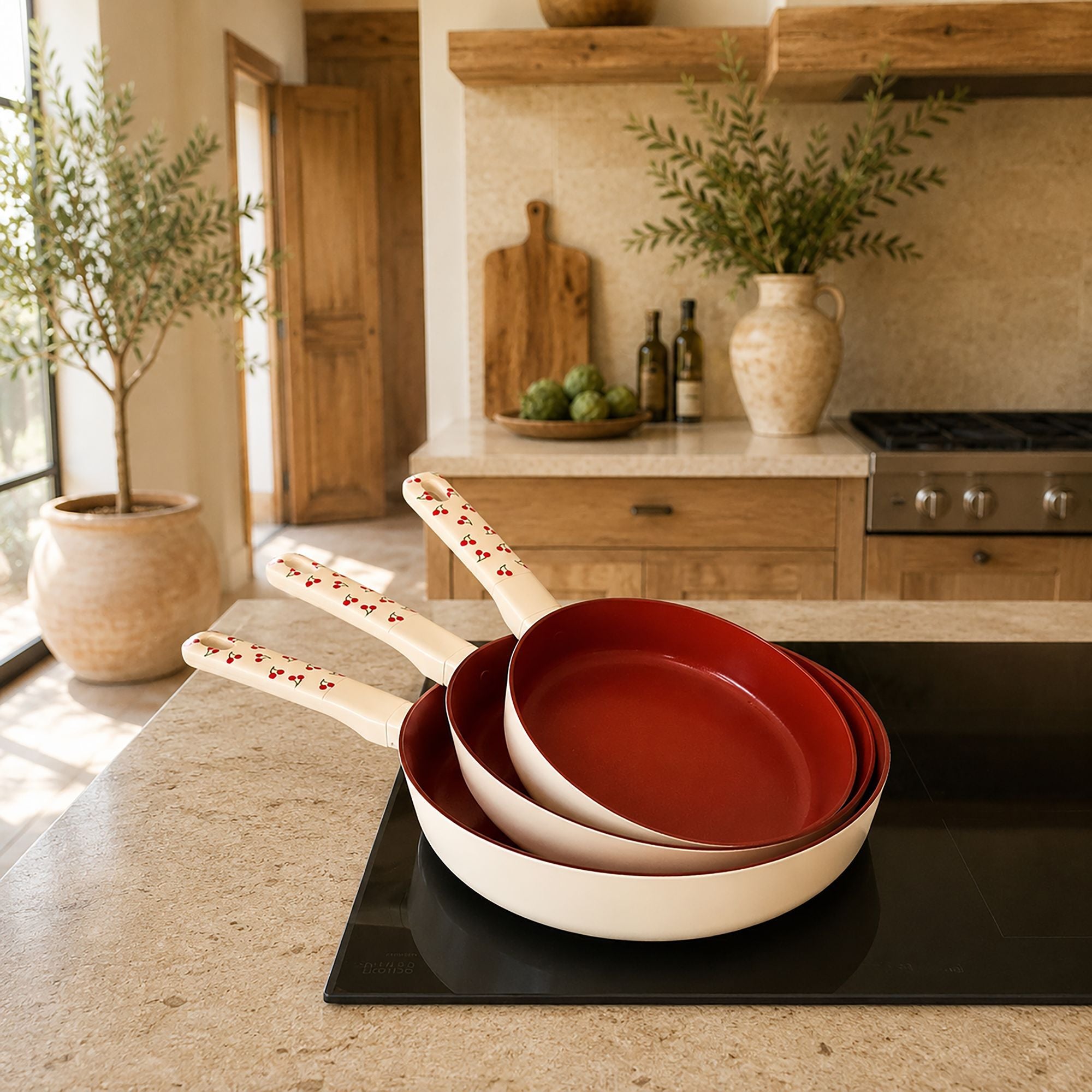 Lot de 3 poêles Cerise empilées avec revêtement rouge intérieur et extérieur blanc à motifs cerises sur comptoir de cuisine