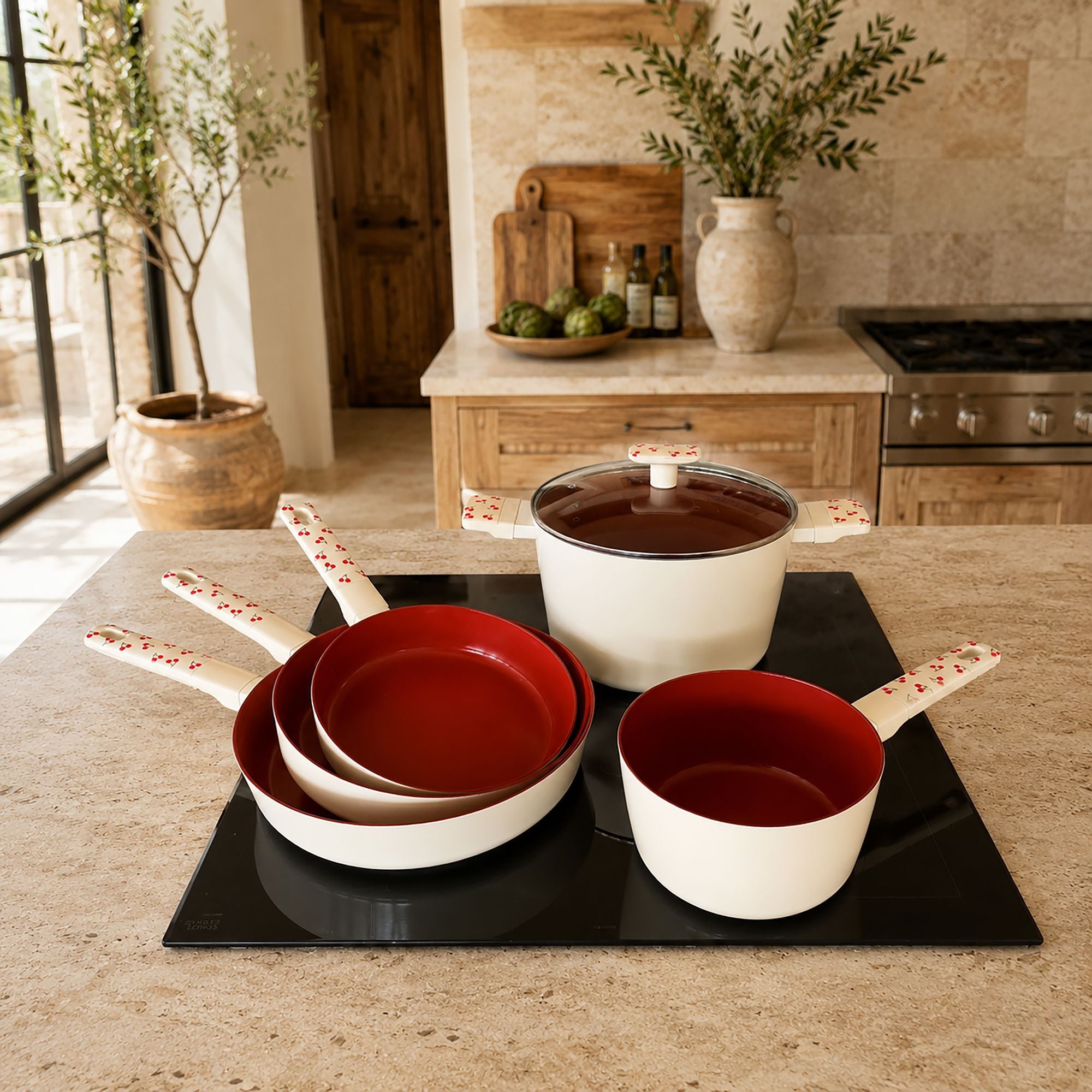 Set de 5 pièces Cerise en aluminium blanc et rouge disposé sur plan de travail, cuisine moderne en arrière-plan