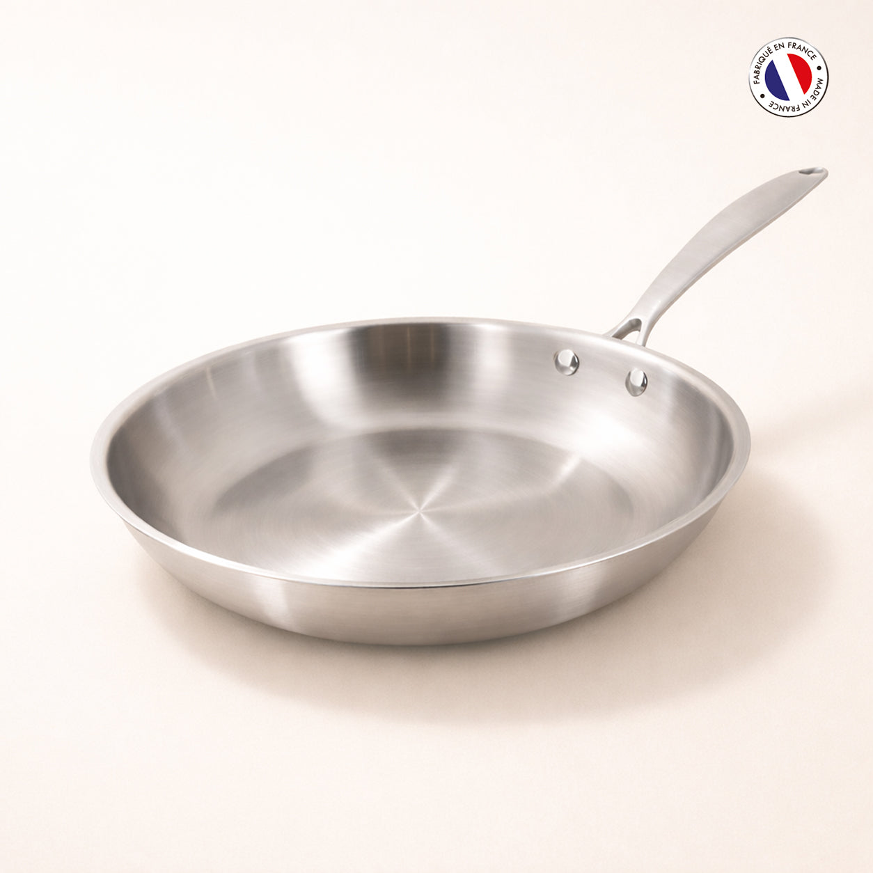 Poêle Triply 24cm en acier inoxydable triple couche Menastyl, vue de trois quarts sur fond clair