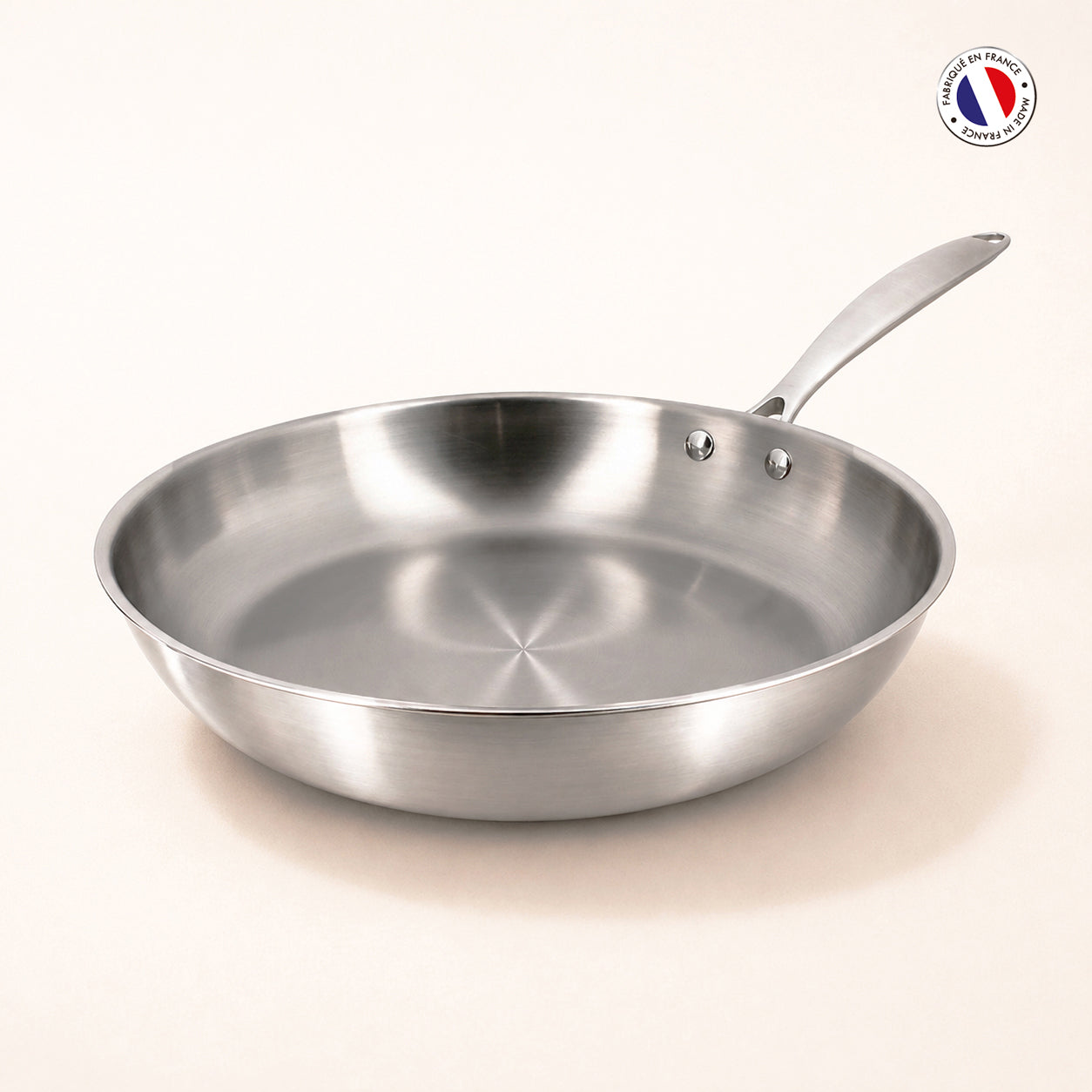 Poêle Triply Menastyl 28 cm en acier inoxydable triple couche, vue de trois-quarts avec manche argenté sur fond clair