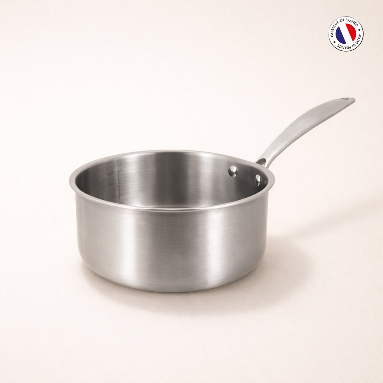 Casserole Triply 16cm en acier inoxydable triple couche Menastyl, vue de trois-quarts sur fond beige