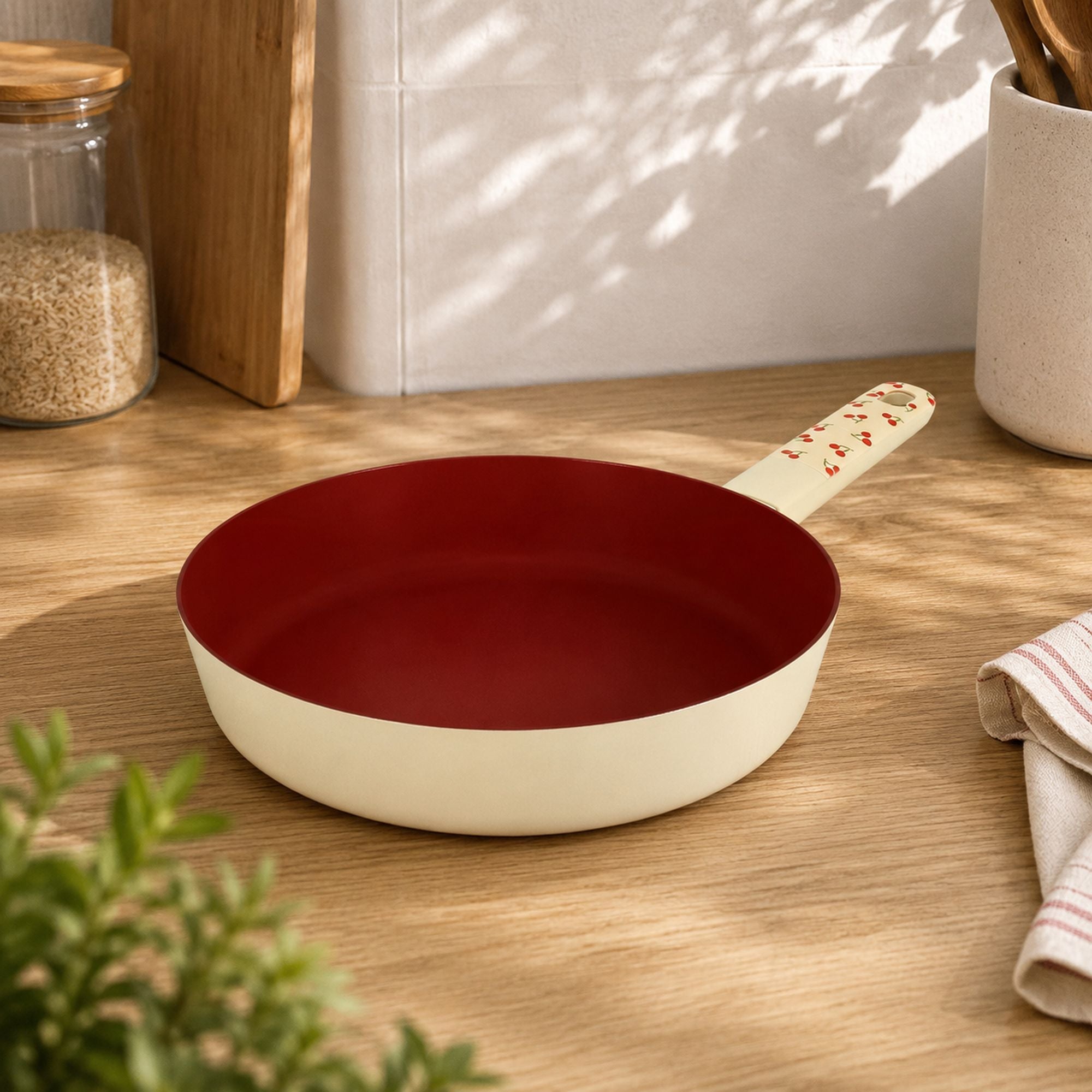 Poêle Cerise 24cm en aluminium posée sur plan de travail bois, intérieur antiadhésif rouge bordeaux