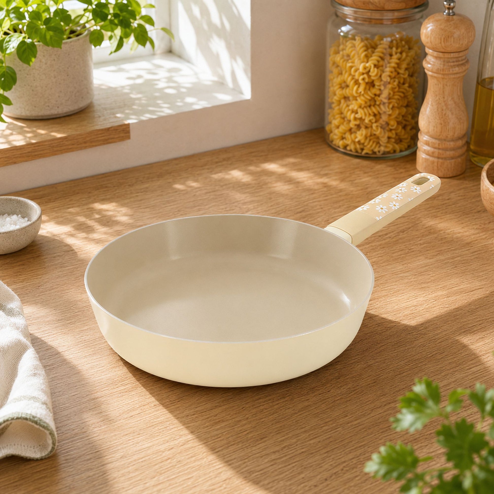 Poêle Marguerite 24cm beige en aluminium posée sur plan de travail bois clair dans cuisine lumineuse