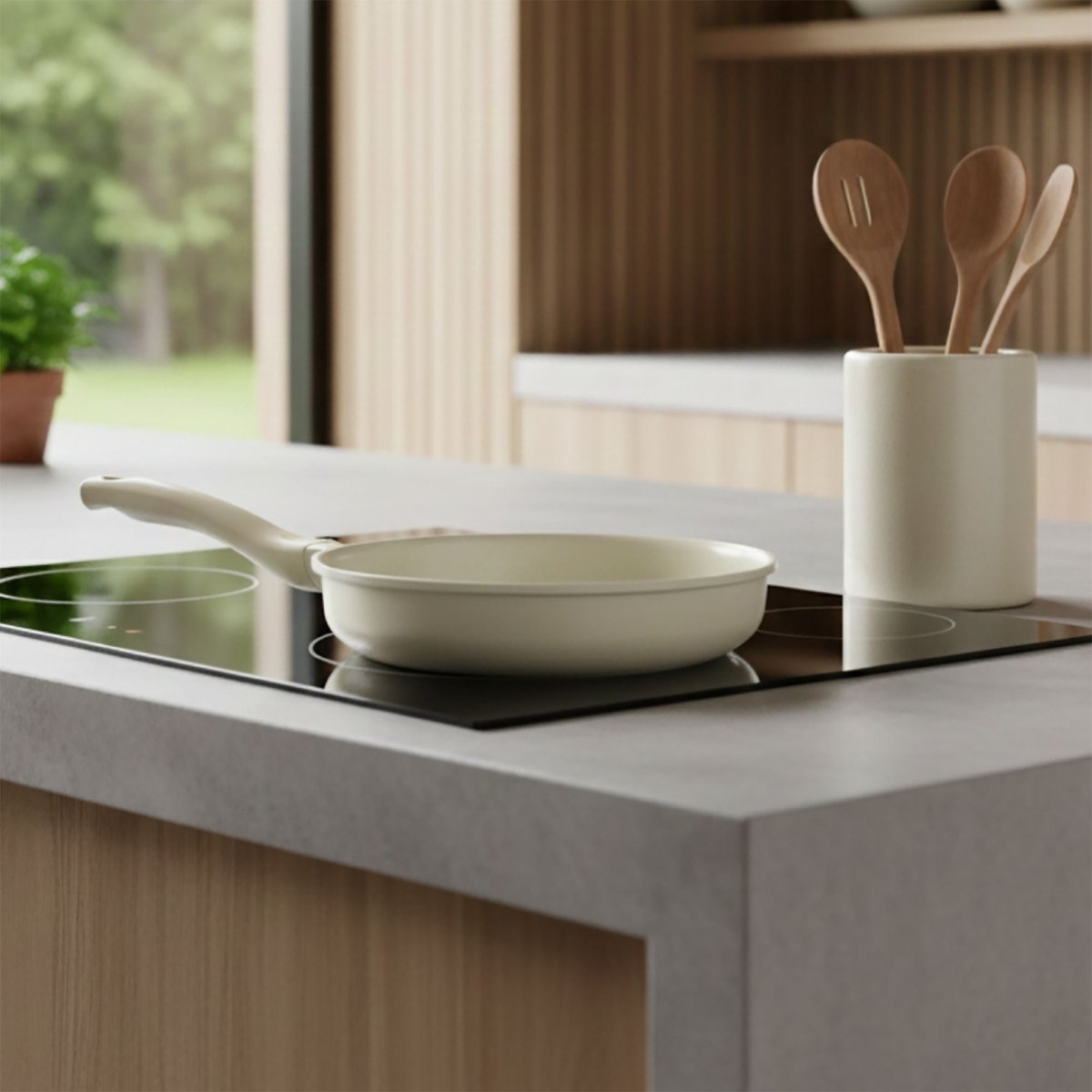 Poêle Pure 28cm crème en fonte d'aluminium recyclé posée sur plaque induction avec ustensiles en bois
