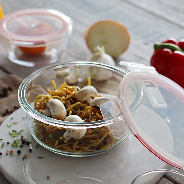 Boîte hermétique ronde en verre avec couvercle transparent contenant des pâtes et champignons, vue détail usage