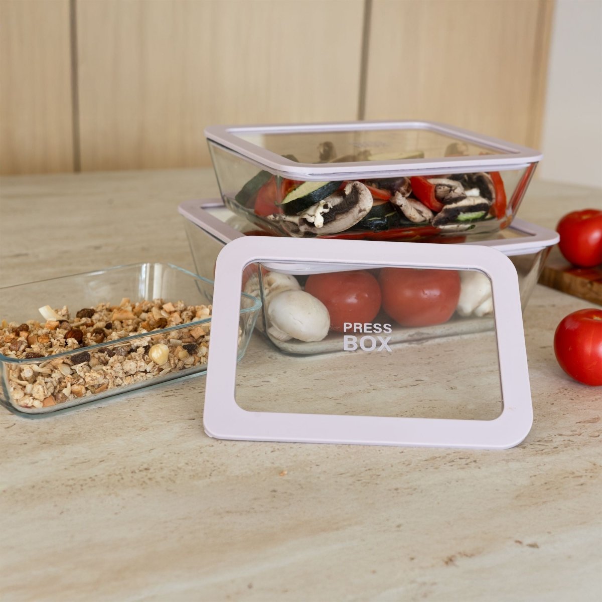 Boîtes hermétiques rectangulaires Pressbox en verre empilées sur plan de travail, contenant légumes et granola