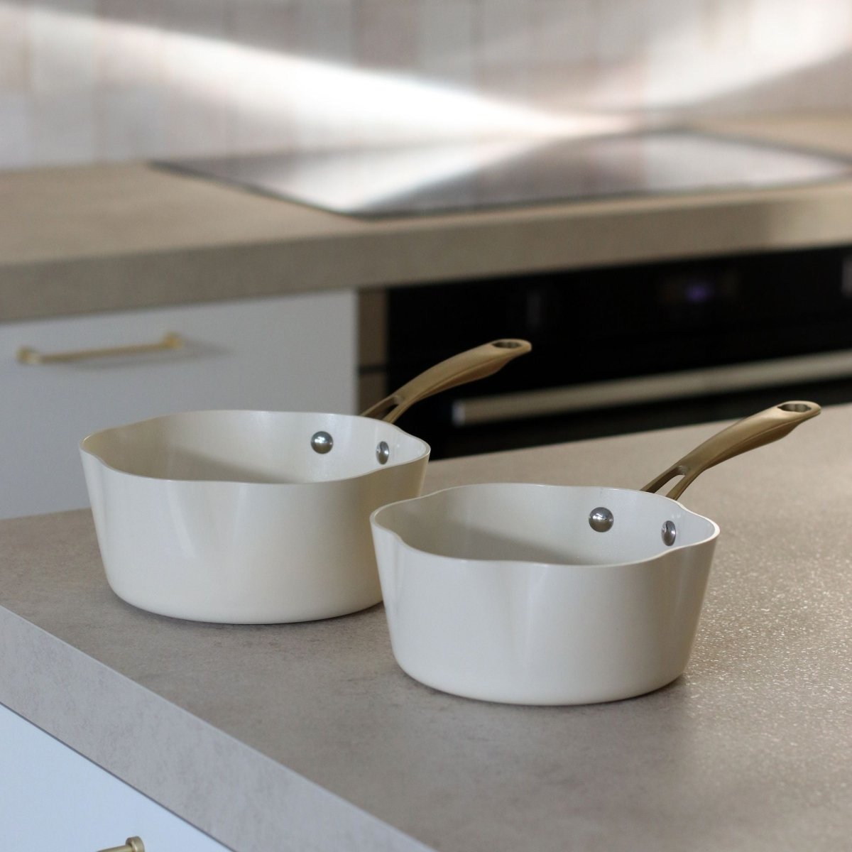 Deux casseroles Dahlia en aluminium recyclé beige avec poignées bois, posées sur plan de travail cuisine moderne