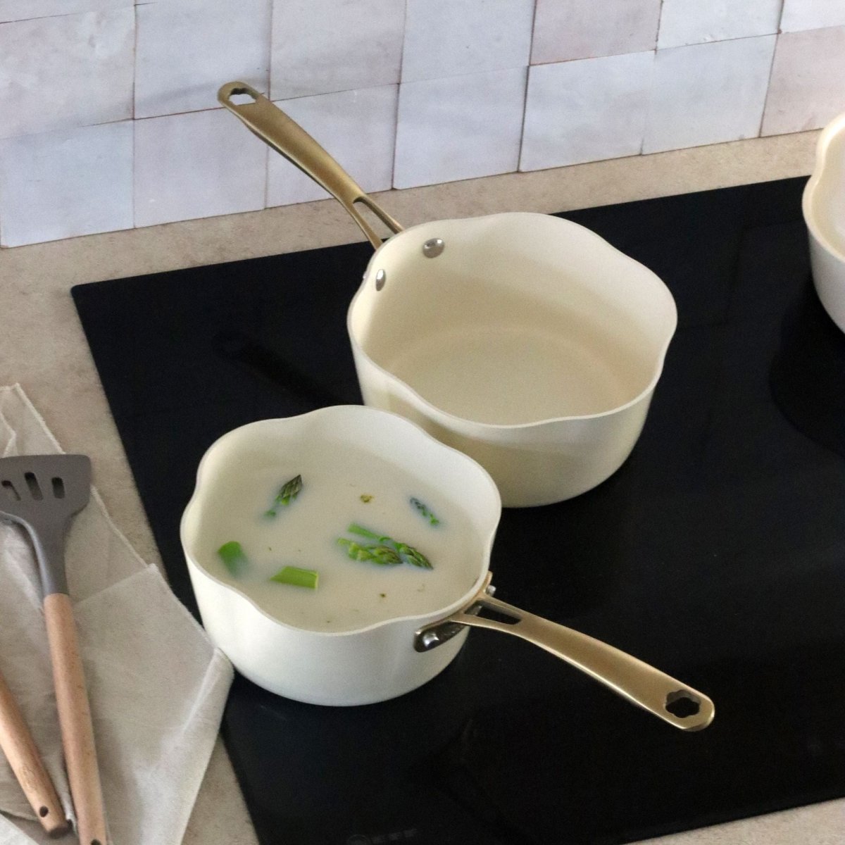 Deux casseroles Dahlia 20 cm beige en aluminium recyclé avec soupe aux asperges, vue de dessus sur plaque de cuisson