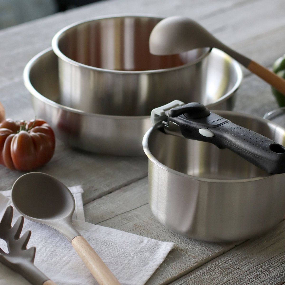 Lot de trois casseroles inox Iris 16, 18 et 20 cm avec poignée amovible noire sur table en bois