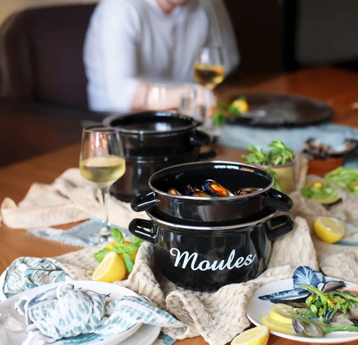 Marmite à moules noire en acier émaillé 18 cm servie avec moules, vin blanc et citron sur table dressée
