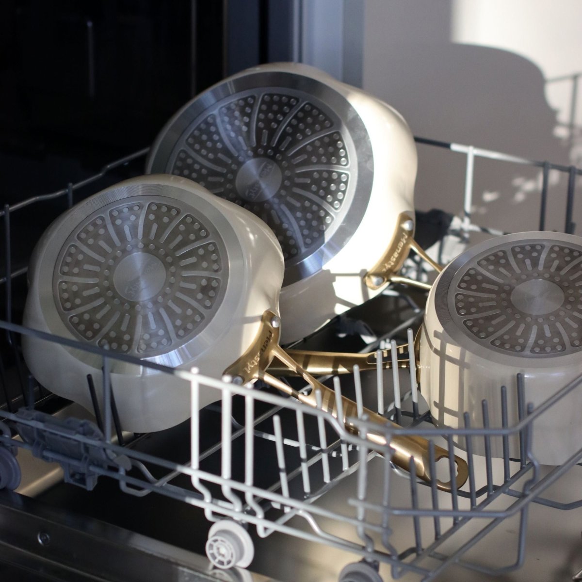 Trois poêles Dahlia 26 cm beige en aluminium recyclé dans un lave-vaisselle, vue intérieure du revêtement antiadhésif
