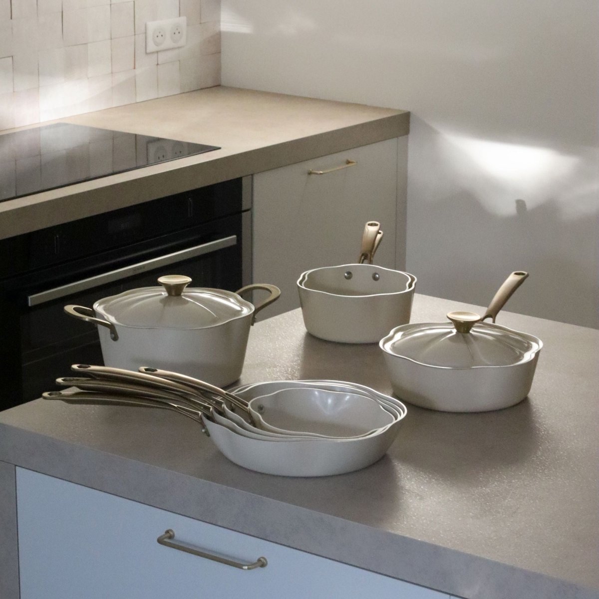 Collection de poêles et casseroles Dahlia beige en aluminium recyclé disposée sur plan de travail cuisine moderne