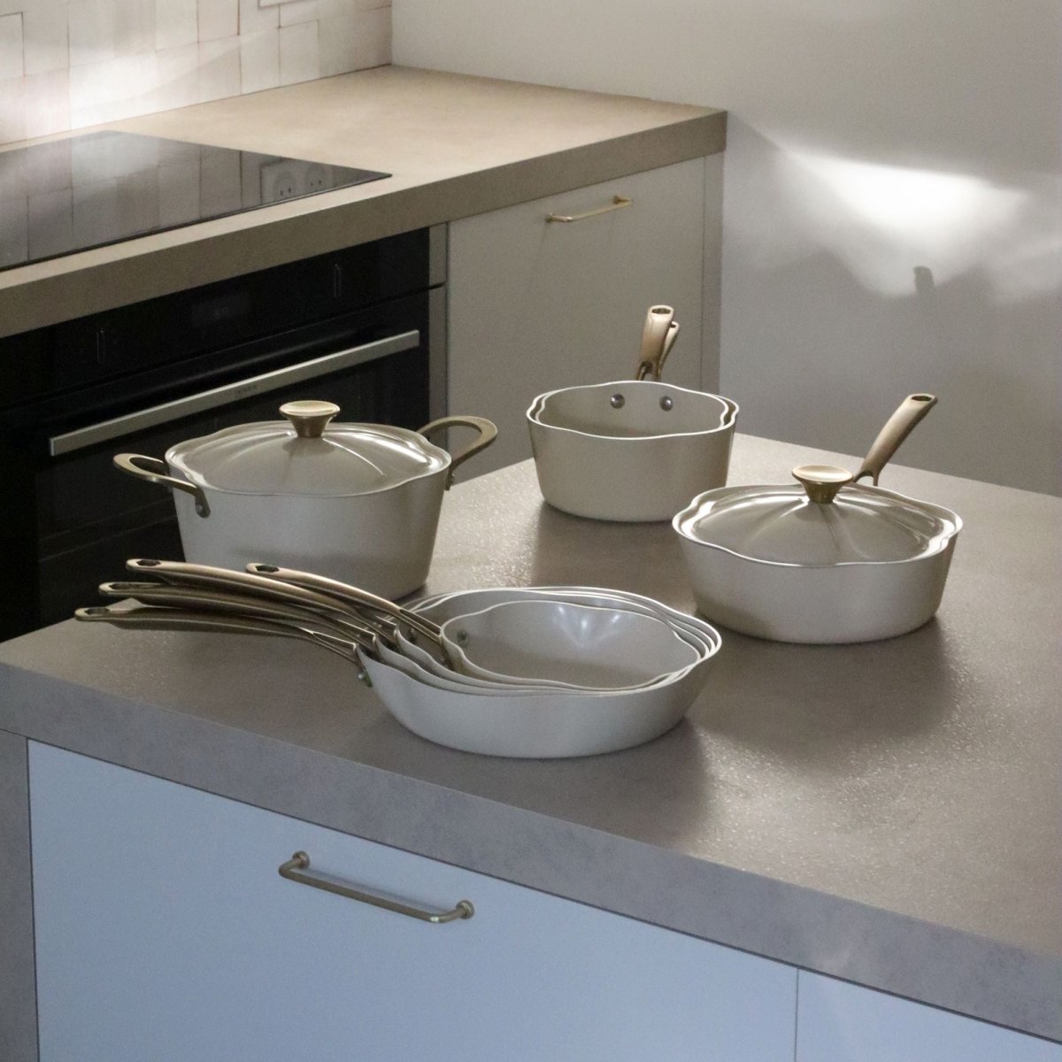 Set de poêles et casseroles Dahlia en aluminium recyclé beige disposé sur plan de travail de cuisine moderne
