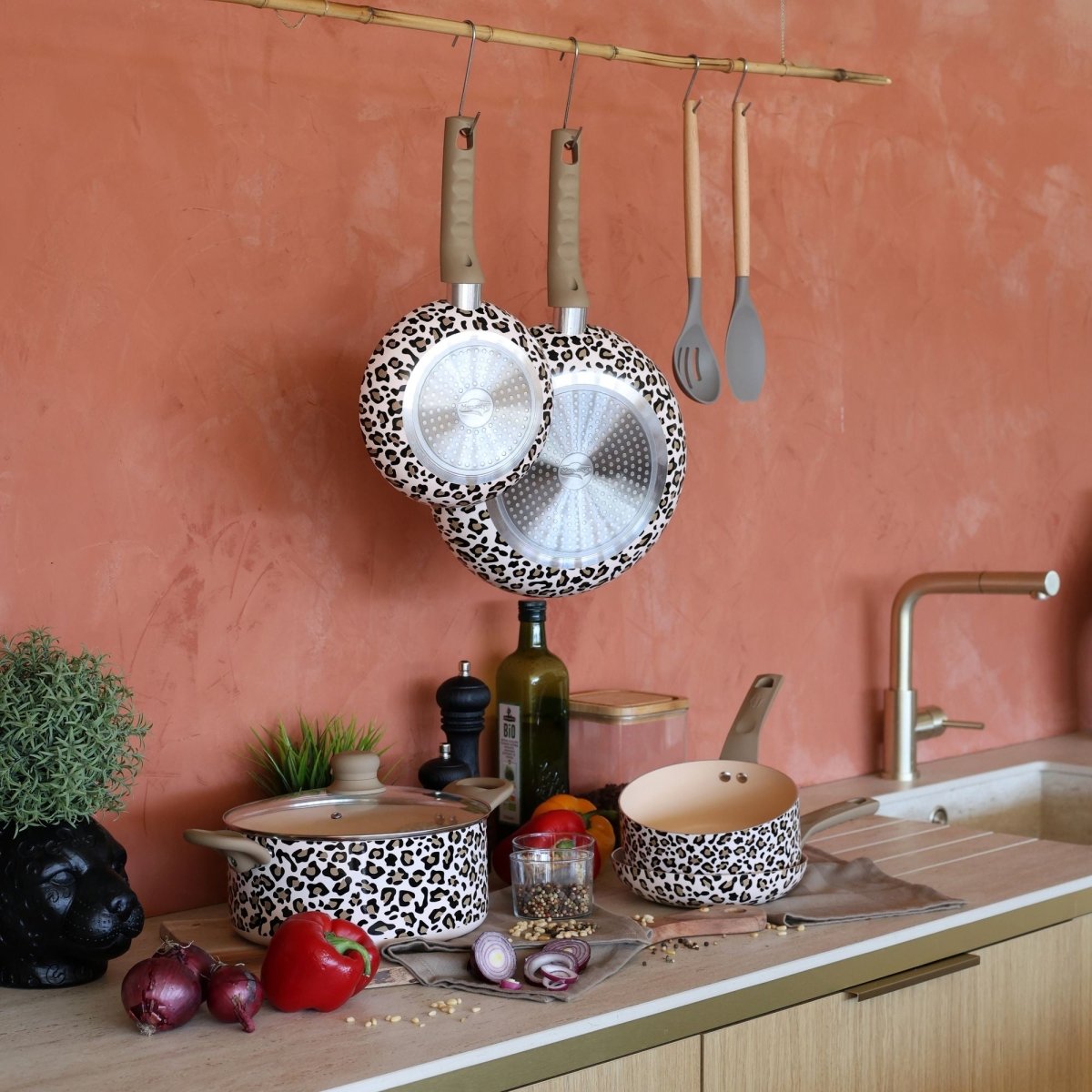 Mise en scène cuisine poêle Léopard marron motif animal avec casseroles et ustensiles suspendus, mur terracotta
