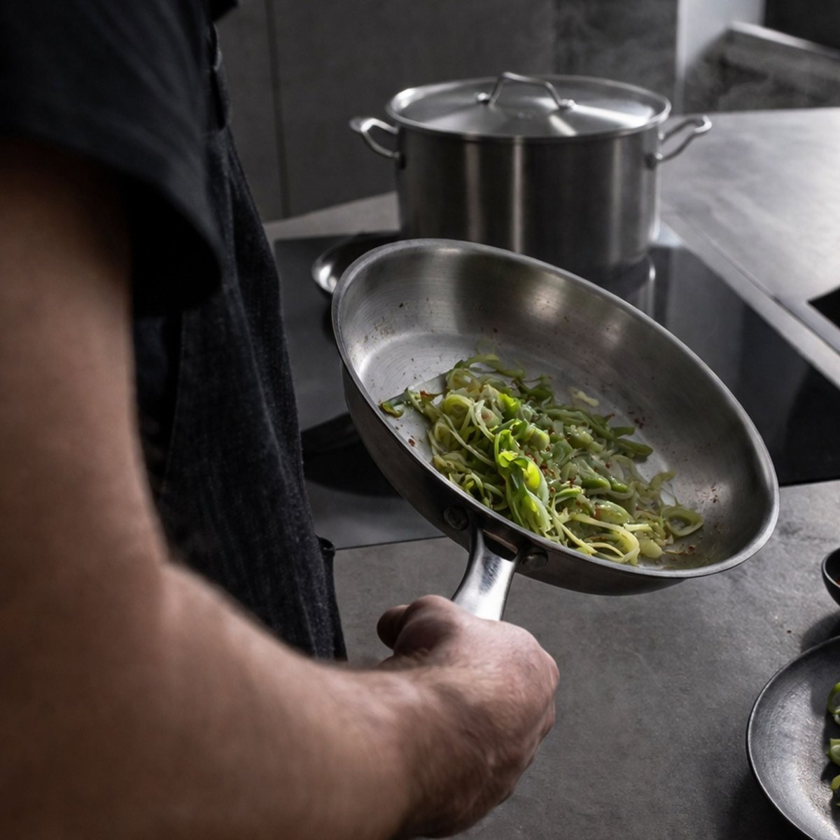 Poêle Triply en acier inoxydable avec légumes sautés, tenue à la main lors de la cuisson