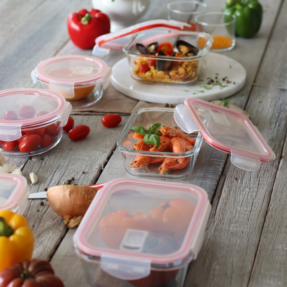 Set de boîtes hermétiques en verre avec couvercles roses sur table en bois, remplies de crevettes et tomates cerises