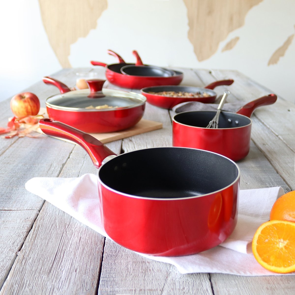 Set de 3 casseroles Cerise rouges en aluminium disposées sur table en bois avec fruits et ustensiles