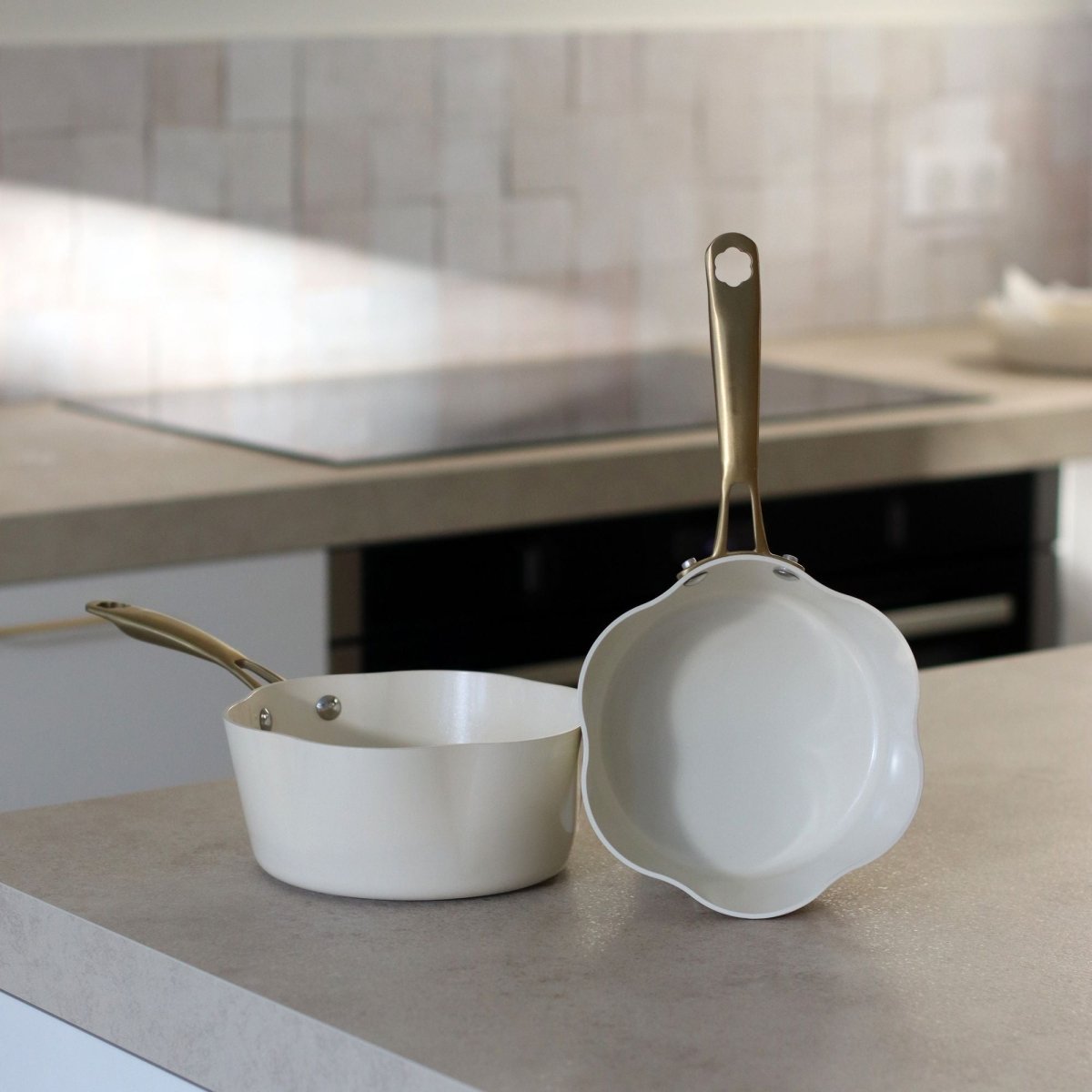 Deux poêles Dahlia beige en aluminium recyclé posées sur plan de travail de cuisine moderne