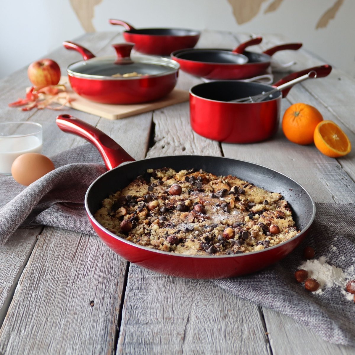 Set 5 pièces Cerise en aluminium rouge, batterie de cuisine disposée sur table en bois avec dessert aux noisettes