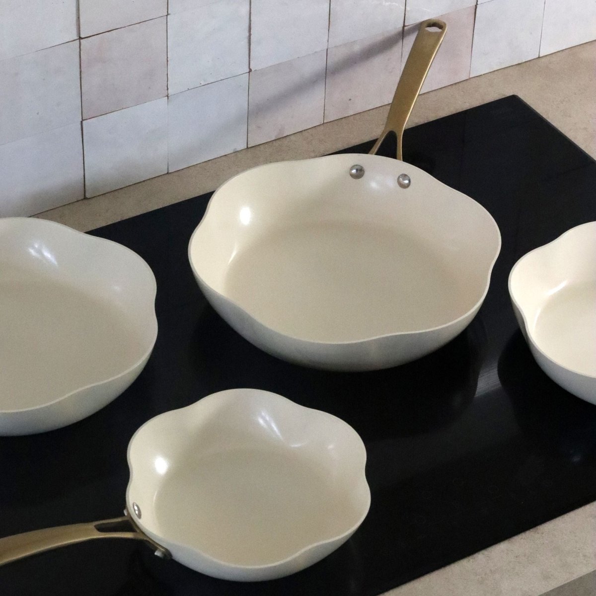 Vue d'ensemble du set 5 pièces Dahlia en aluminium recyclé beige disposé sur comptoir noir de cuisine