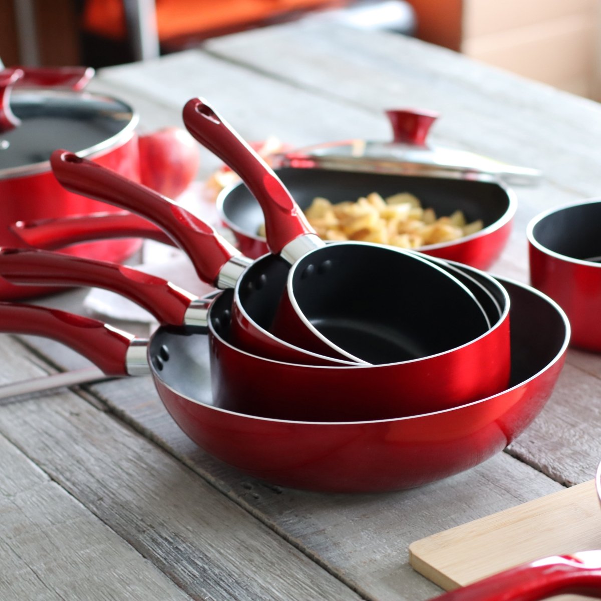 Set de 7 pièces Cerise aluminium rouge disposé sur table en bois, casseroles poêles et wok compatibles induction
