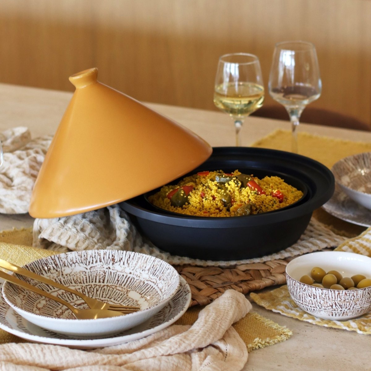Tajine en aluminium noir 30cm avec couvercle conique ouvert, plat cuisiné aux légumes et couscous, table dressée
