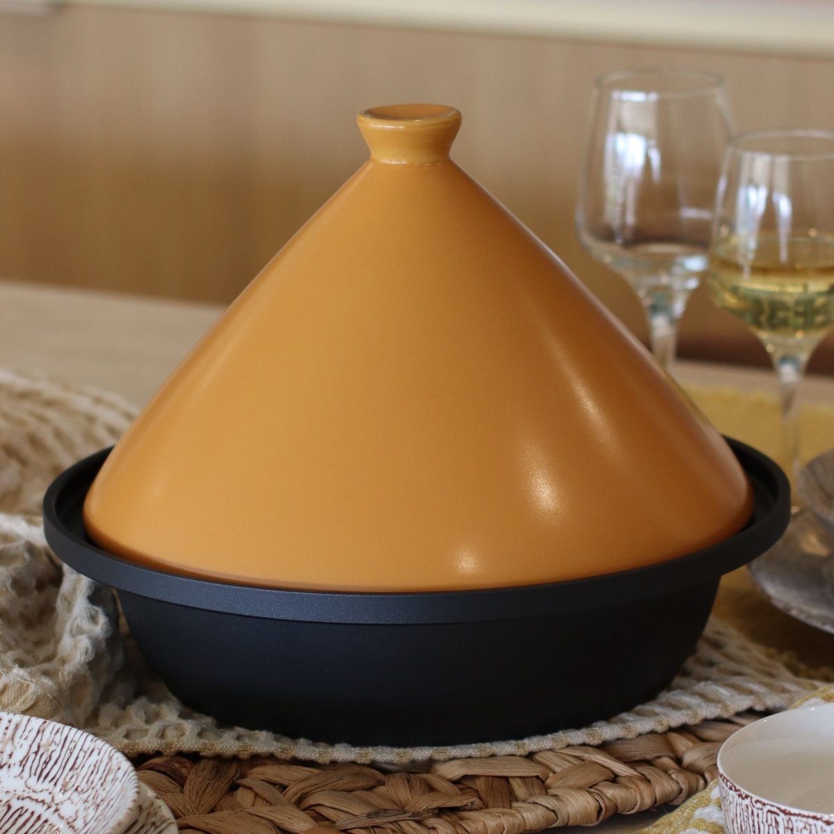 Tajine en aluminium 30 cm avec couvercle conique orangé posé sur table dressée, vue de trois-quarts