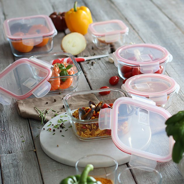 Set de boîtes hermétiques en verre avec couvercles roses disposées sur table en bois avec légumes frais